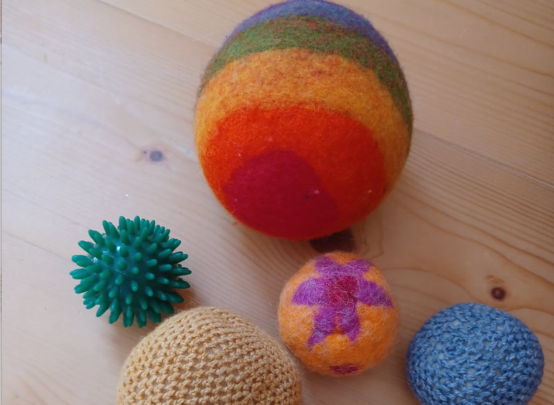 Bunte Filzbälle und Igelbälle auf einem Holzboden